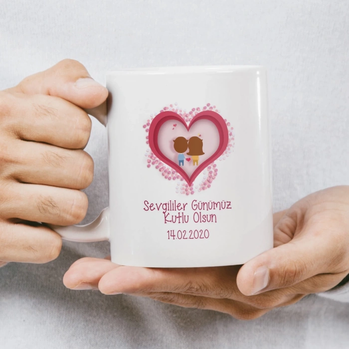 İsimlerin iç kısımda, etrafı kalplerle çevrili pembe bir kalple süslenmiş kupa baskısı.