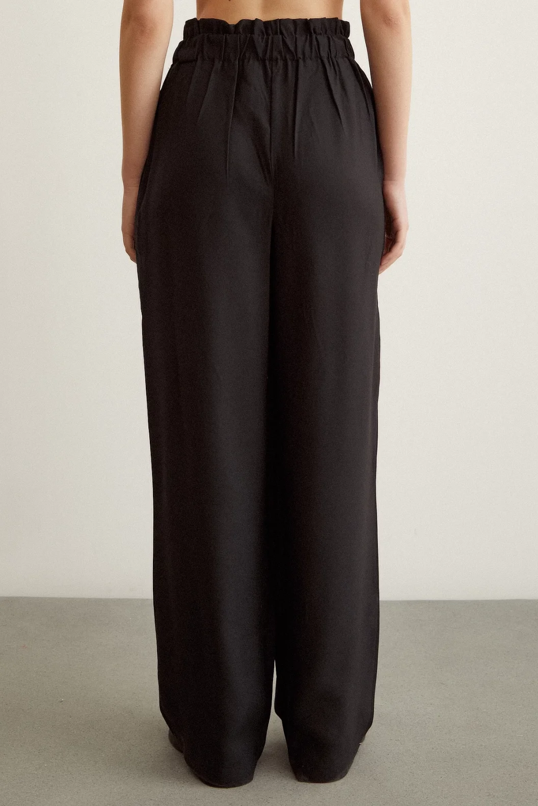 بنطال أسود مع تفاصيل أزرار مطاطية وتنورة مجسمة